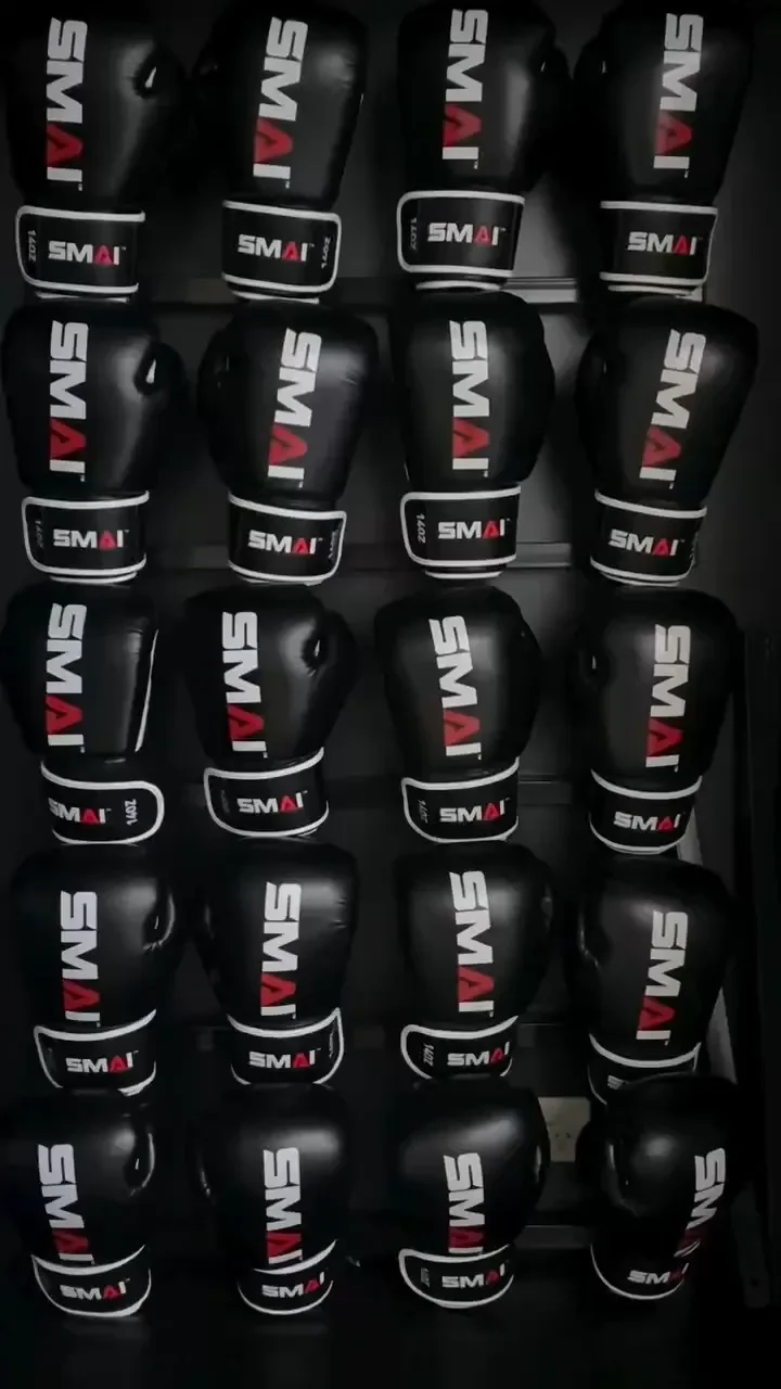 Row of black MMA gloves with white and red branding on a display shelf.
