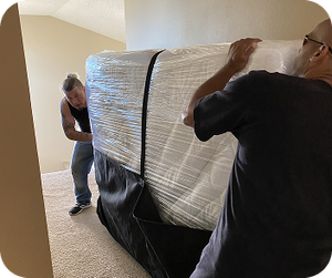 Movers handling a large wrapped household item