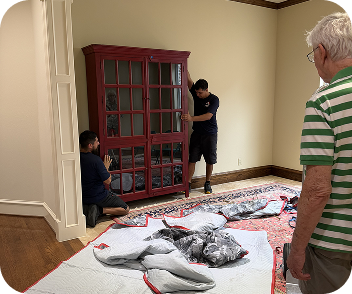 Senior movers handling a wooden display cabinet
