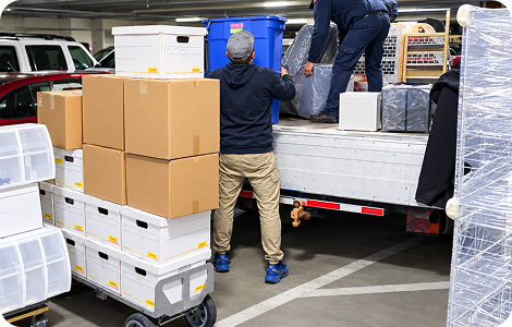 Heavy item movers loading bulky boxes into a truck