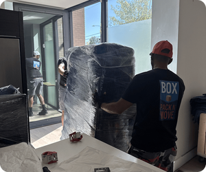 Gun safe movers guiding a wrapped safe through a doorway