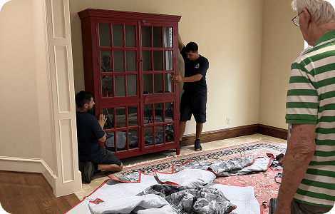 Senior movers handling a wooden display cabinet