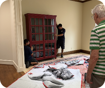 Senior movers handling a large wooden cabinet