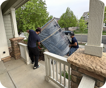 Residential movers carrying large wrapped furniture