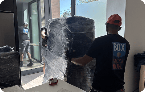 Movers carrying large wrapped furniture
