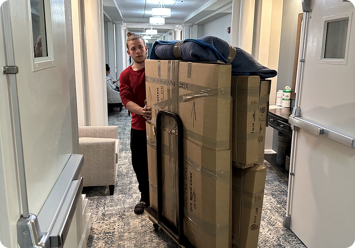 Movers transporting packed boxes on a dolly