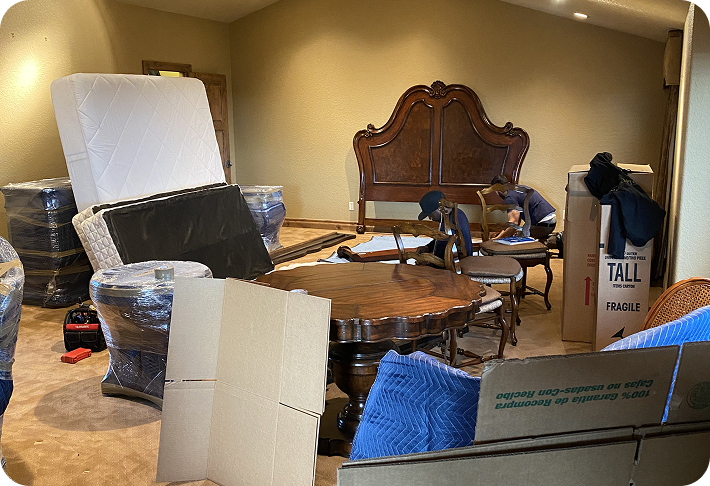 Long distance movers carrying cardboard boxes across a porch