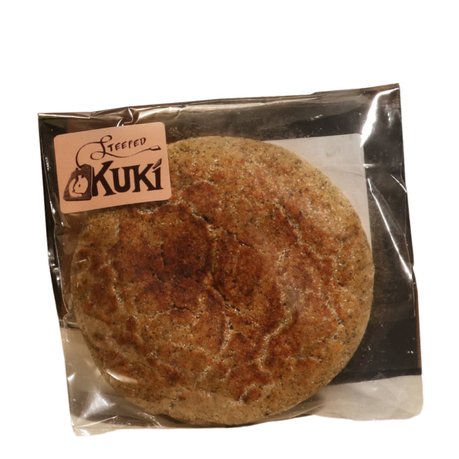 A packaged frozen crab cake in clear plastic with a label reading 'Steeped Kuki' in black font and an illustration of a crab claw and shell.