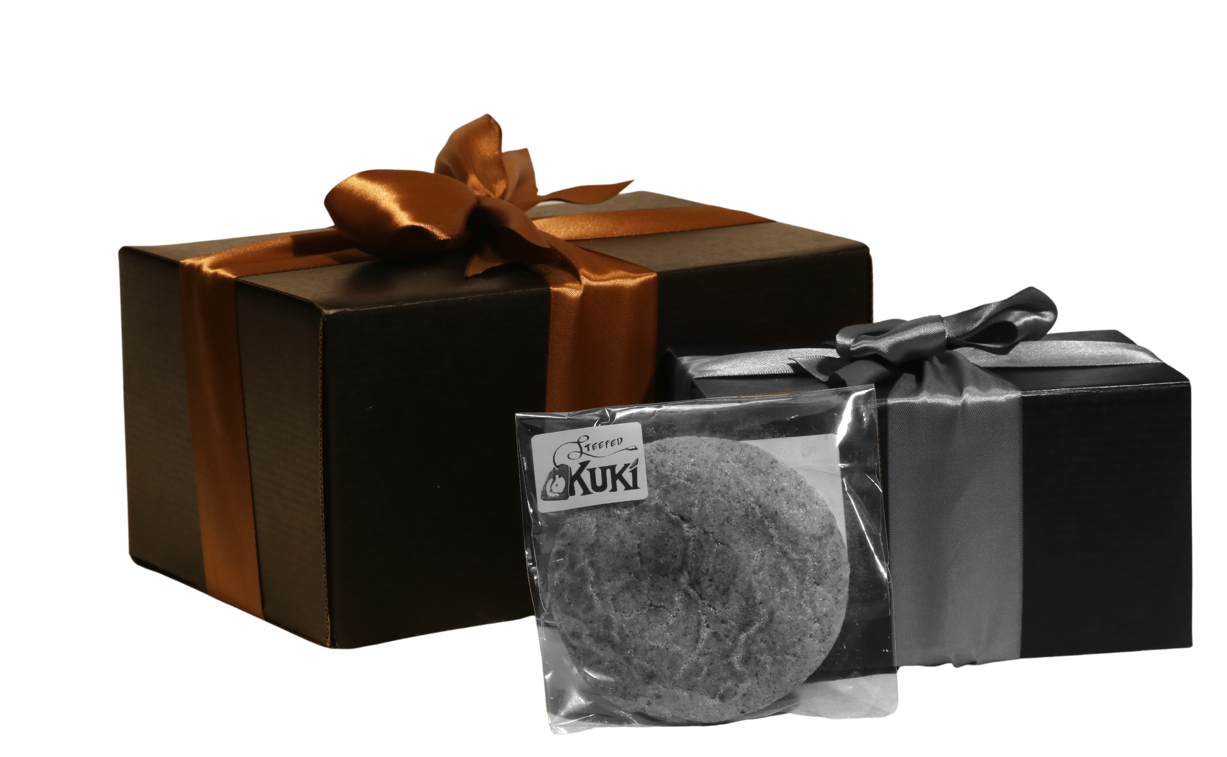 Two gift boxes, one black with a copper-colored satin ribbon and bow, and another smaller black box with a matching satin ribbon, with a clear plastic bag of Kukireep salted bread crumbs in front.