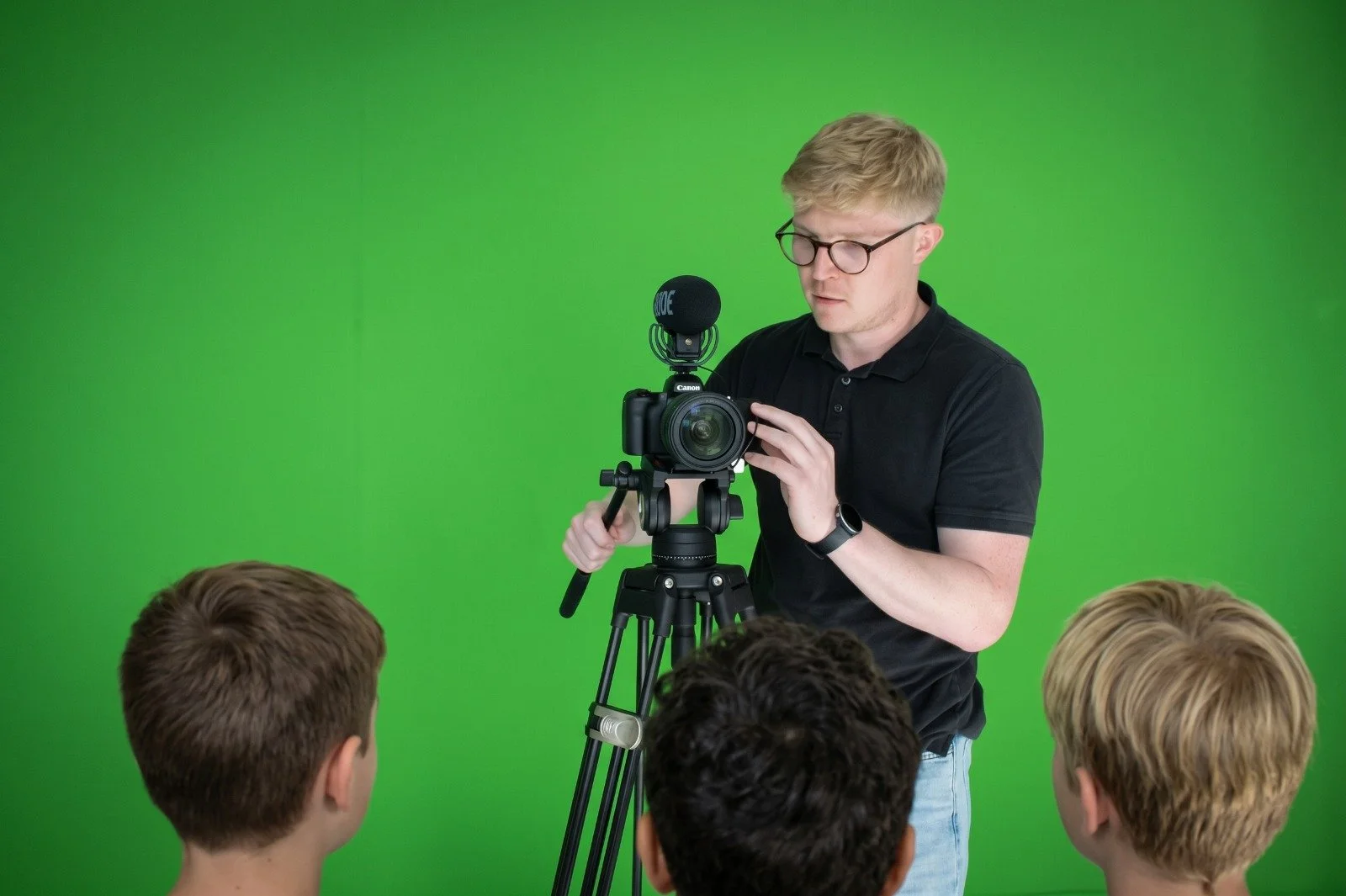 Connor Keal filming a group of kids with a professional camera and microphone against a green screen background.