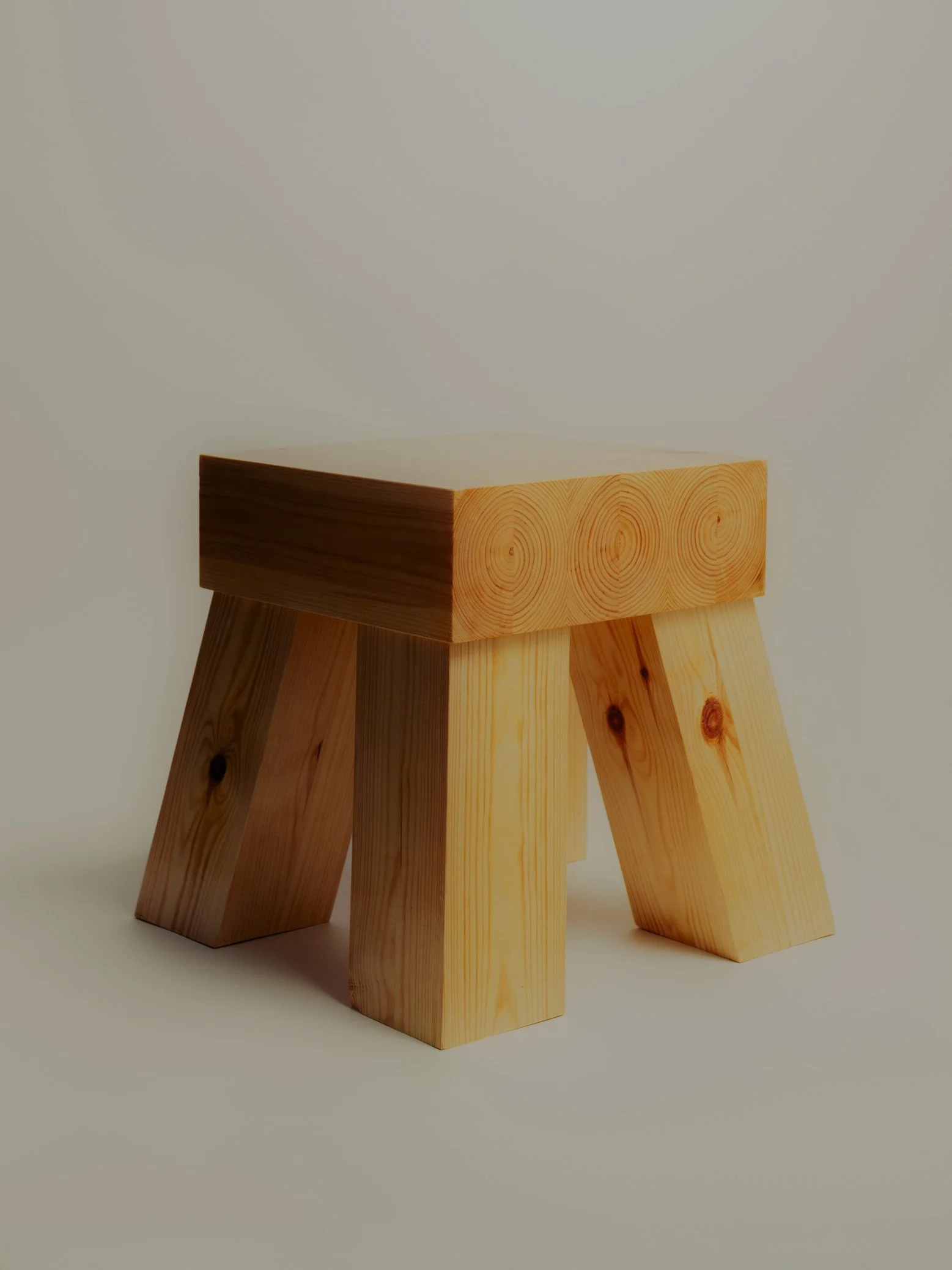 Three wooden stools with angled legs placed on a plain background.