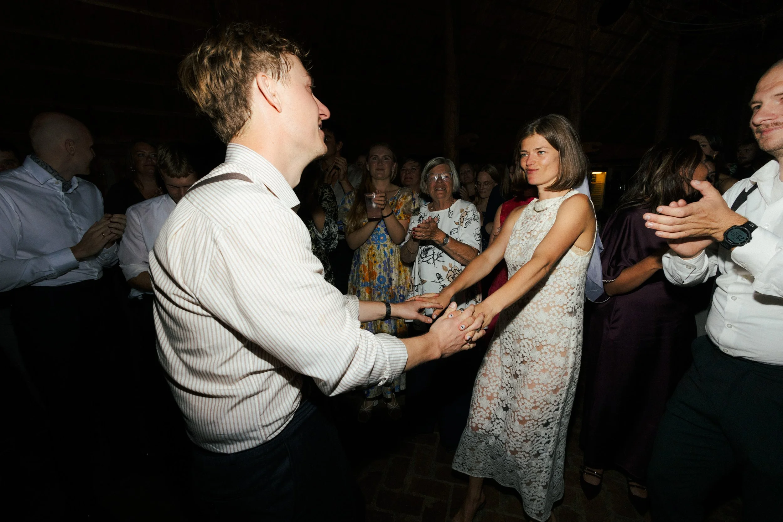 Mennesker danser og får håndfast i en festlig indendørs begivenhed.
