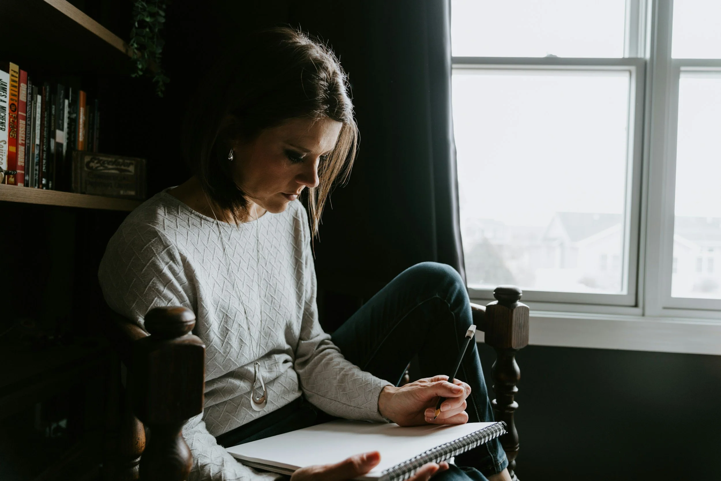 Person writing in a notebook by a window, representing HAELM's practice of writing down ad readings