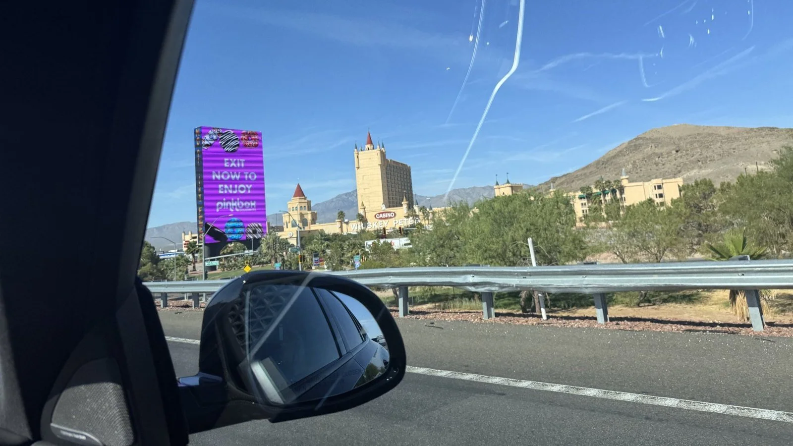 Interstate 15 near Primm, Nevada, seen from a car window: a castle-style casino hotel, a guardrail and the car's side mirror.