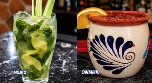 Un vaso con mojito con menta, limón y hielo, y un cacito de cantaro con salsa roja y una rodaja de naranja.