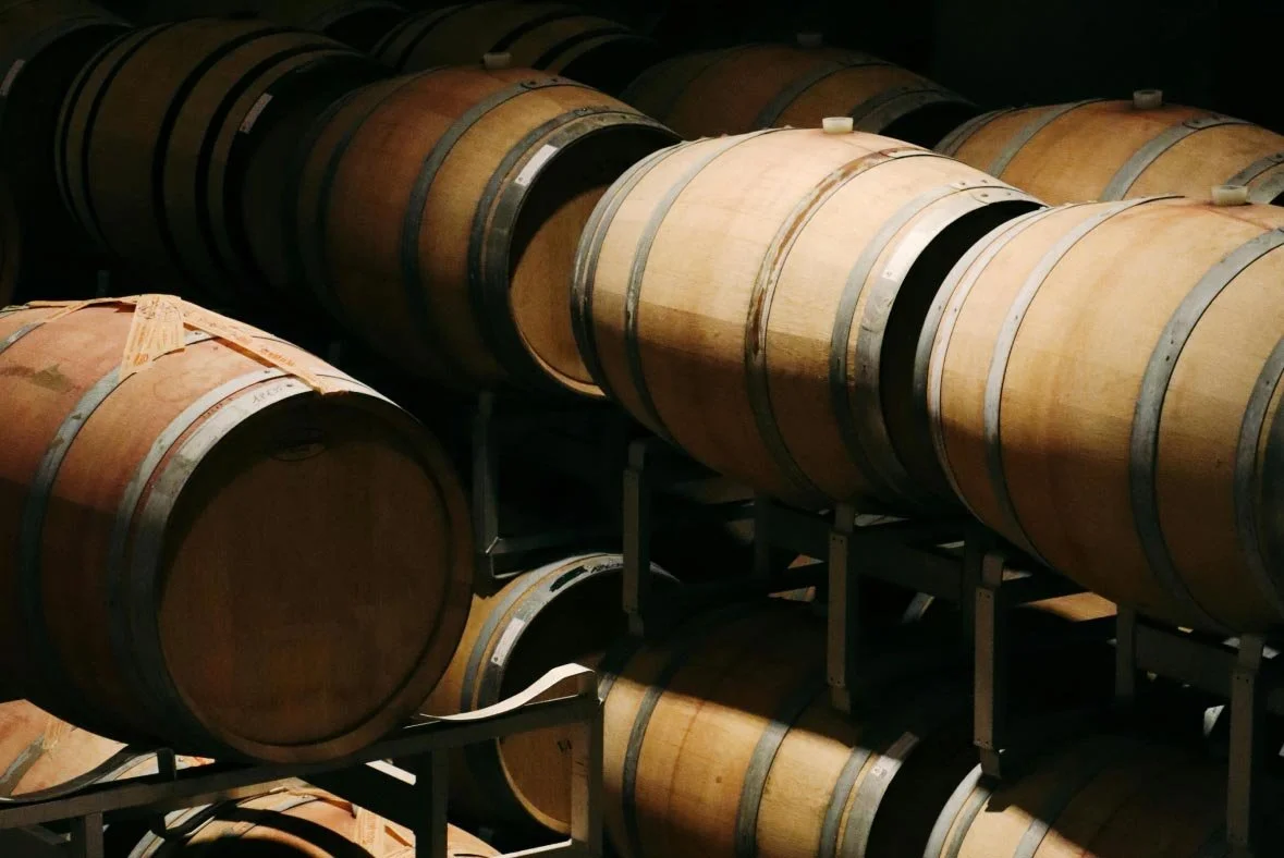 Wine barrels stored on racks in a winery or cellar.