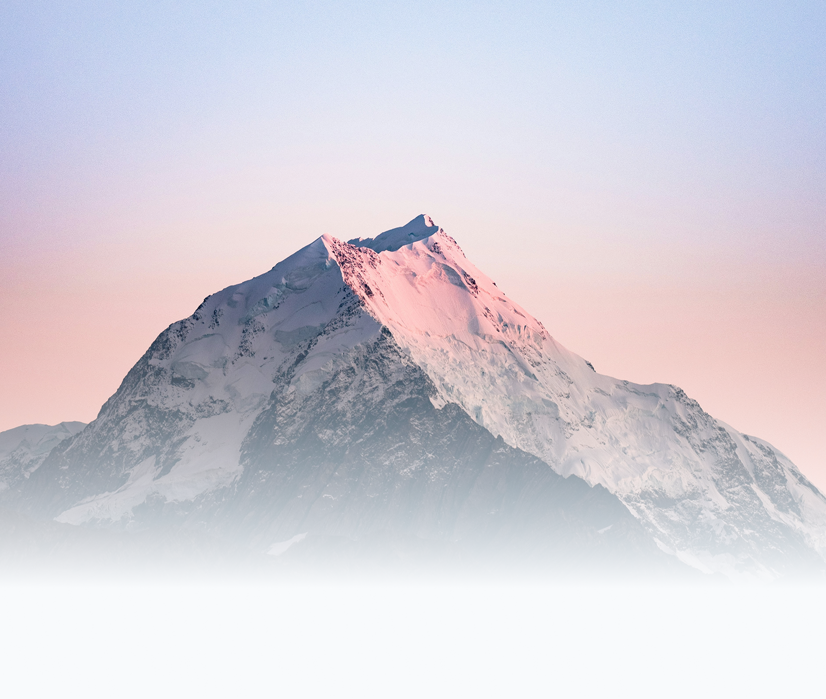 Snow-capped mountain peak during pink and blue sunset.