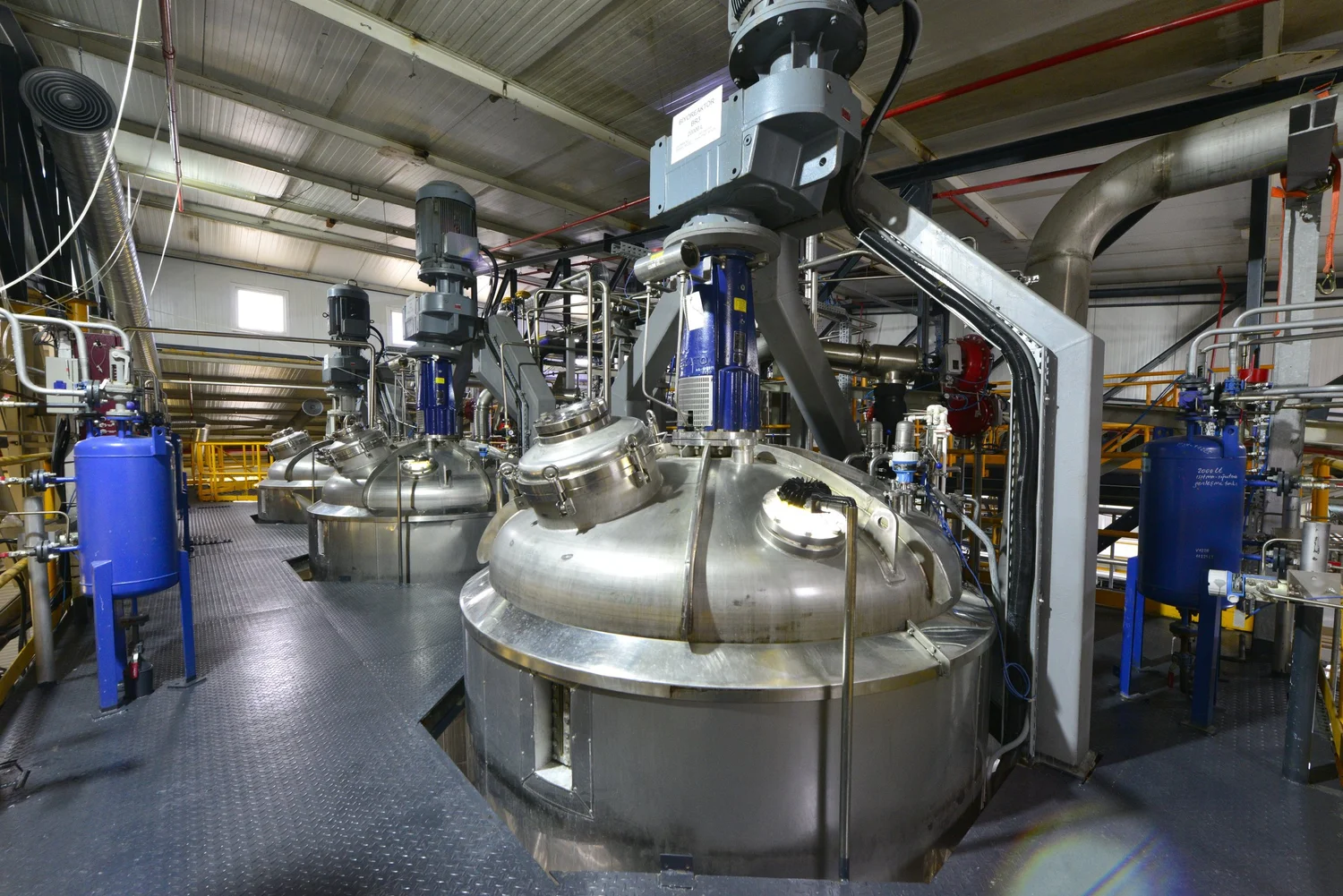 Large stainless steel production fermenters with top-mounted agitator drives in Livzym's fermentation hall