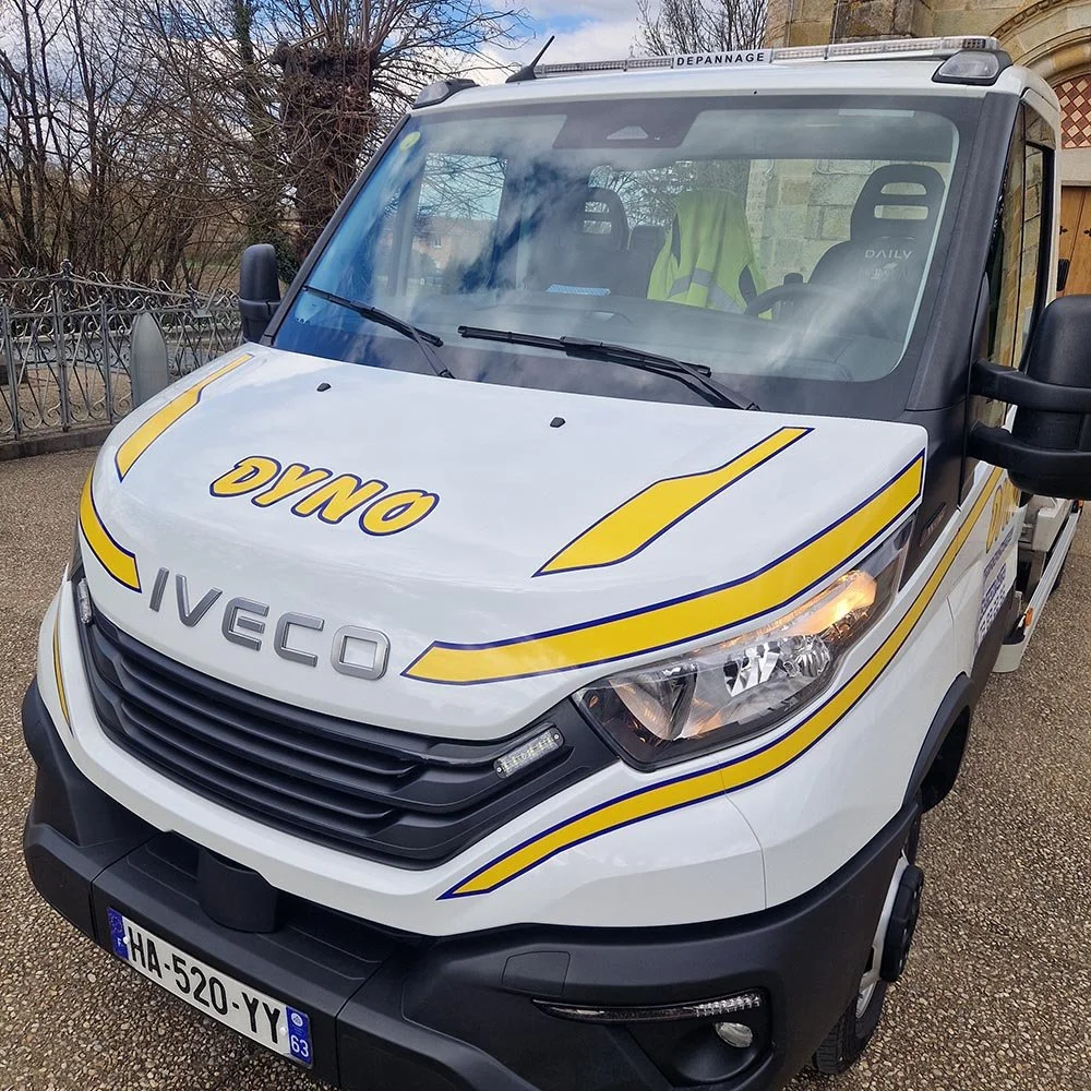 Véhicule de service avec marquages « DYNO » et « IVECO », à l'extérieur, avec un badge de plaque d'immatriculation français HA-520-YY.