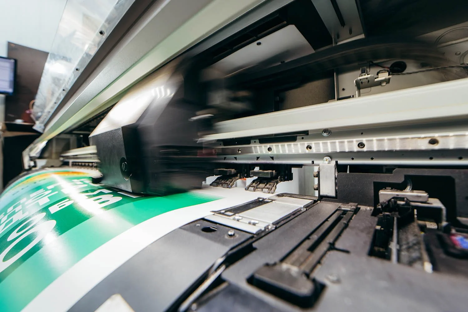 Impression d'une machine à imprimer qui imprime un large ruban vert avec du texte blanc dans un atelier de fabrication d'étiquettes.