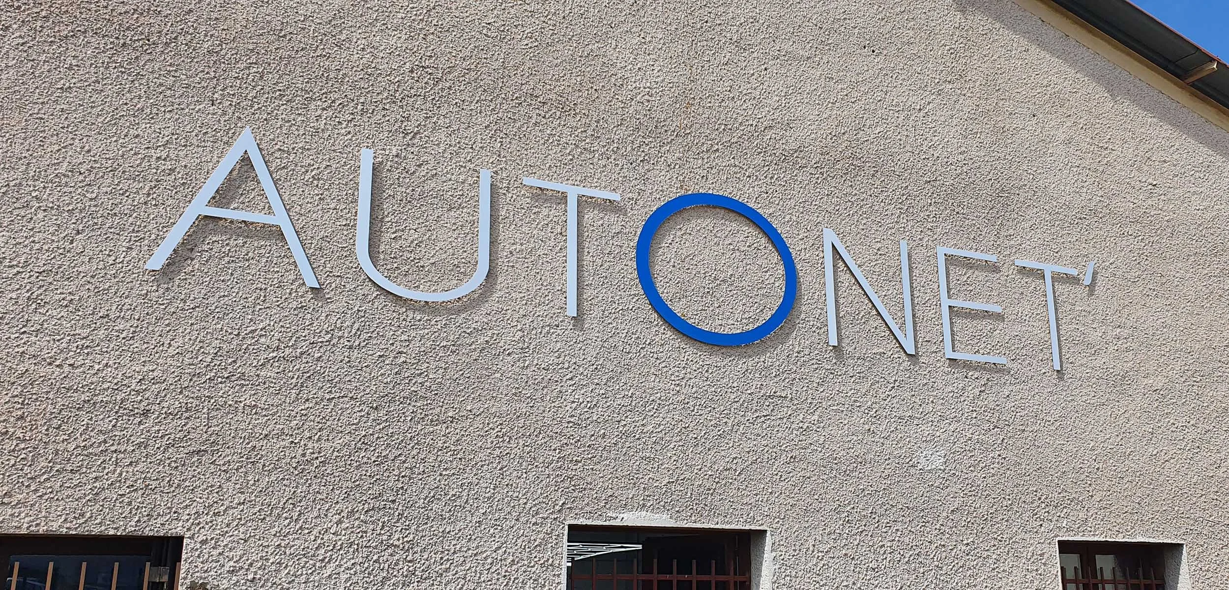 Signer le panneau du centre culturel nommé 'AutoNet' sur un mur en béton beige.