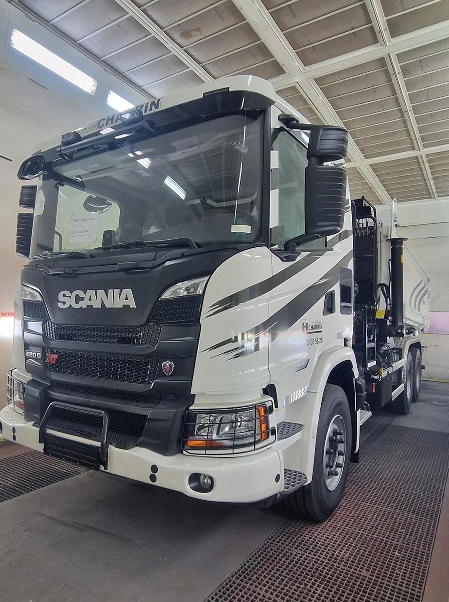 Un camion blanc de marque Scania stationné à l'intérieur, dans un bâtiment.