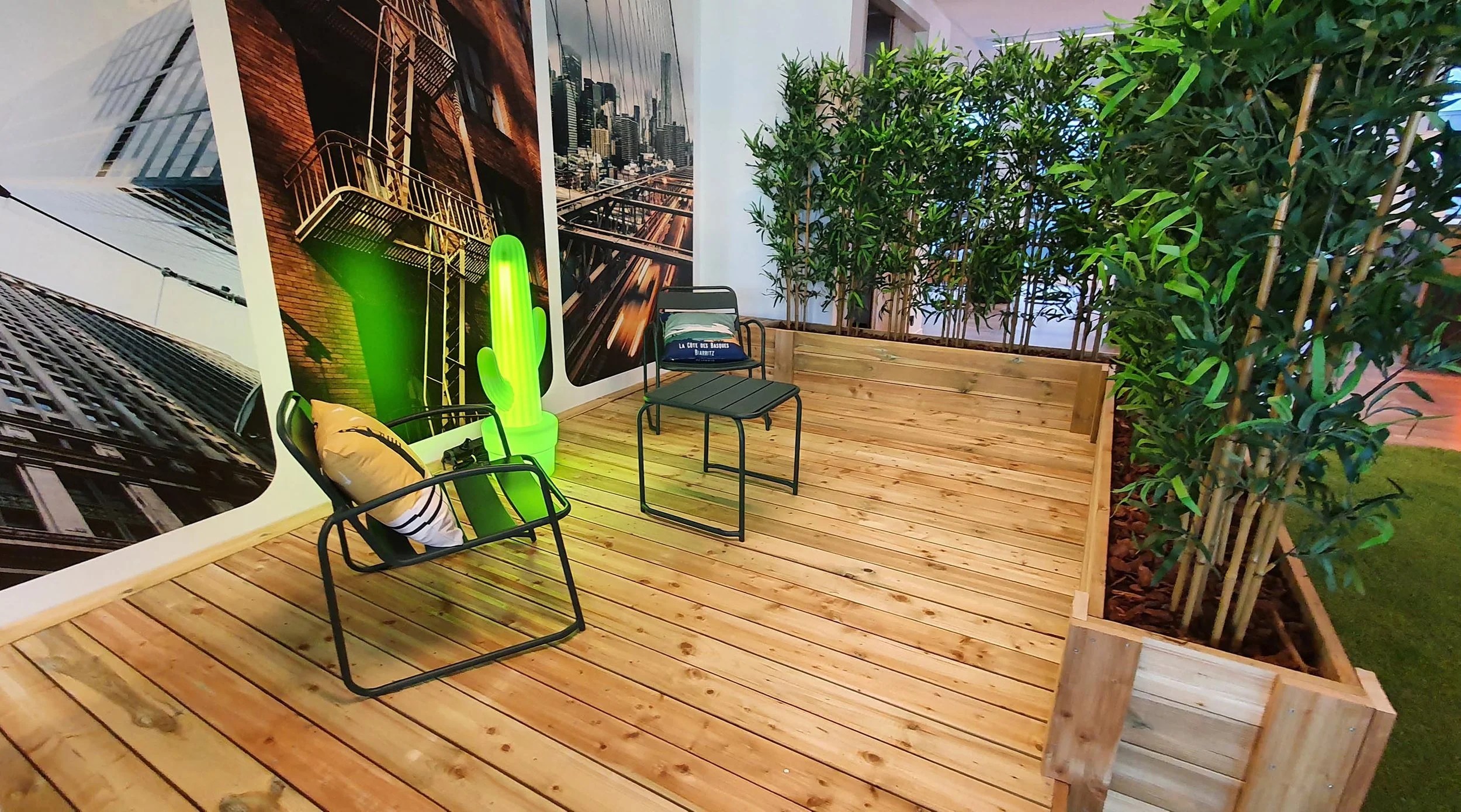 Installation d'un espace de travail chaleureux mettant en scene une terrasse en bois et un décor végétal.