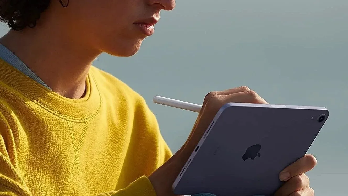 Person in a yellow sweater using an iPad mini with an Apple Pencil
