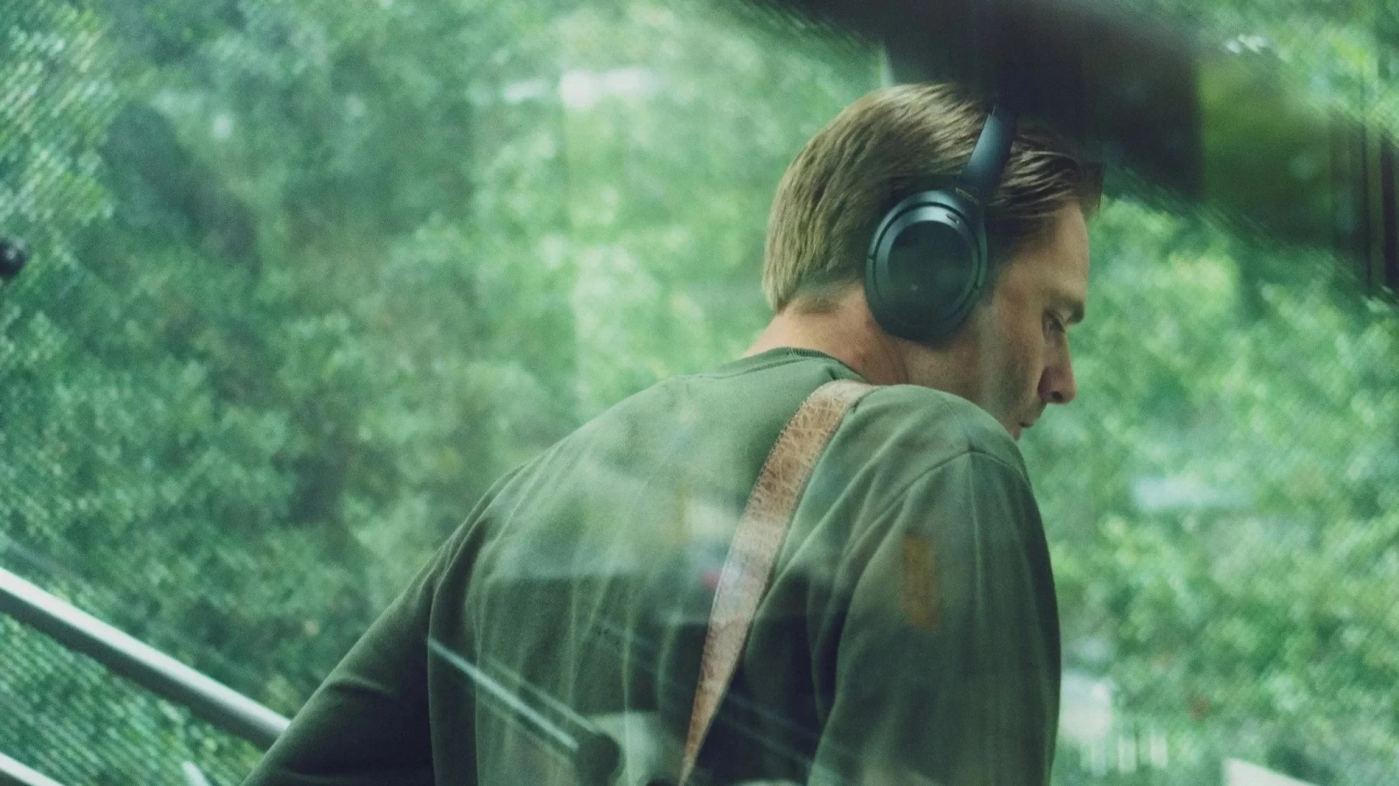 Man wearing over-ear headphones looking out a window