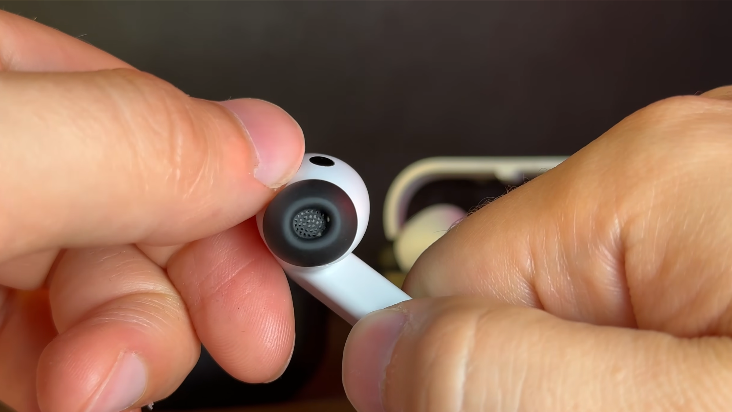 Hands holding a white earbud