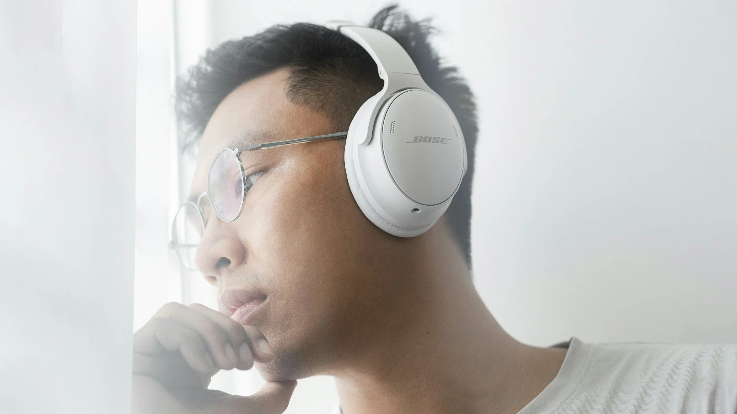 A young Asian man wearing a pair of white Bose headphones