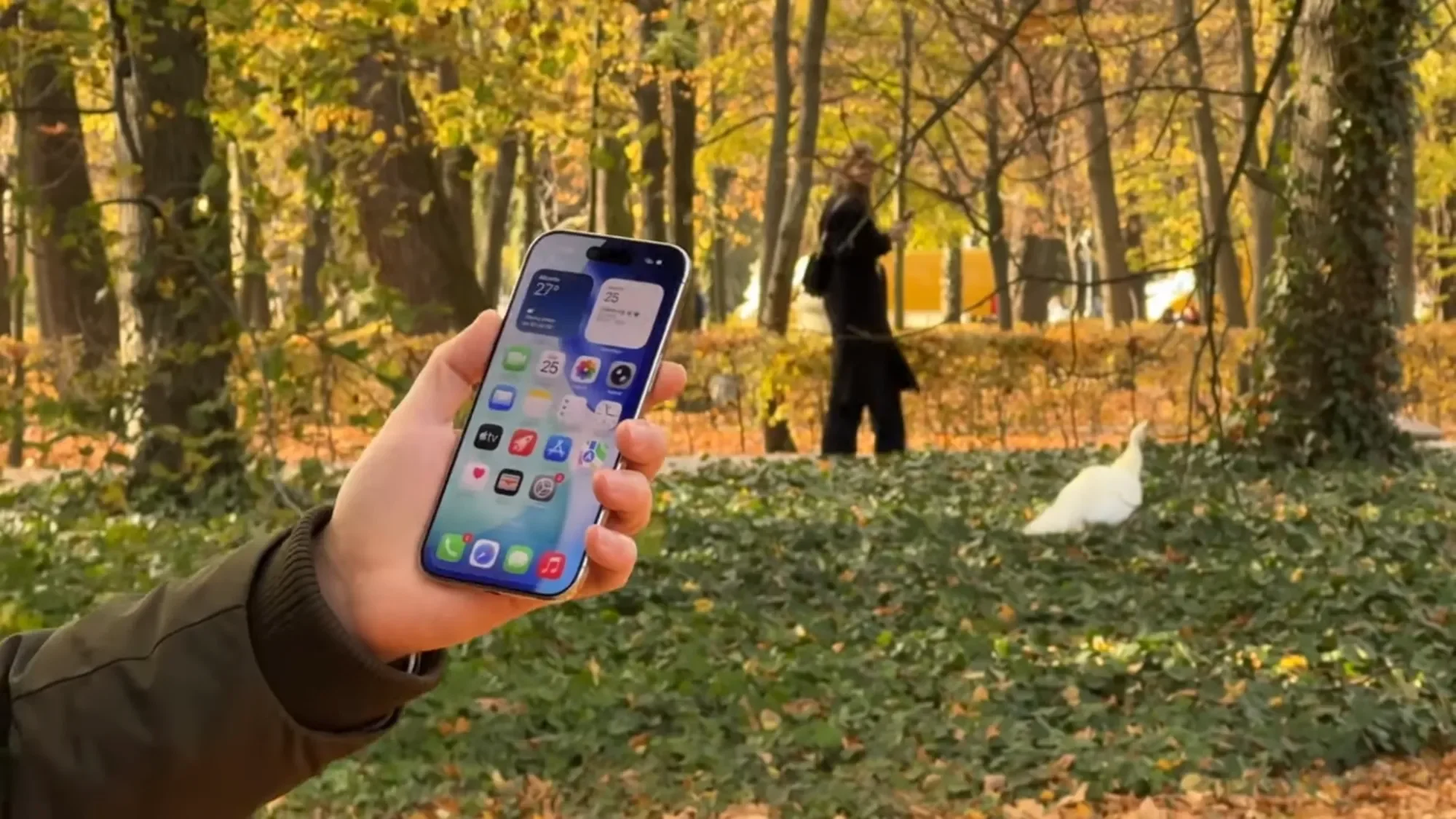 Hand holding an iPhone Air in an autumn park