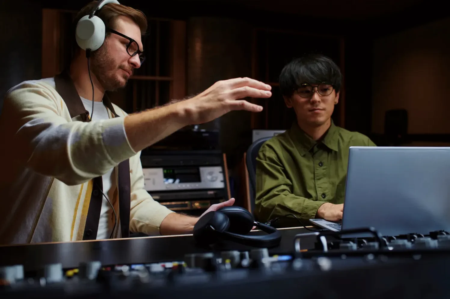 Two people working in a music studio, one wearing Sony 1000X headphones