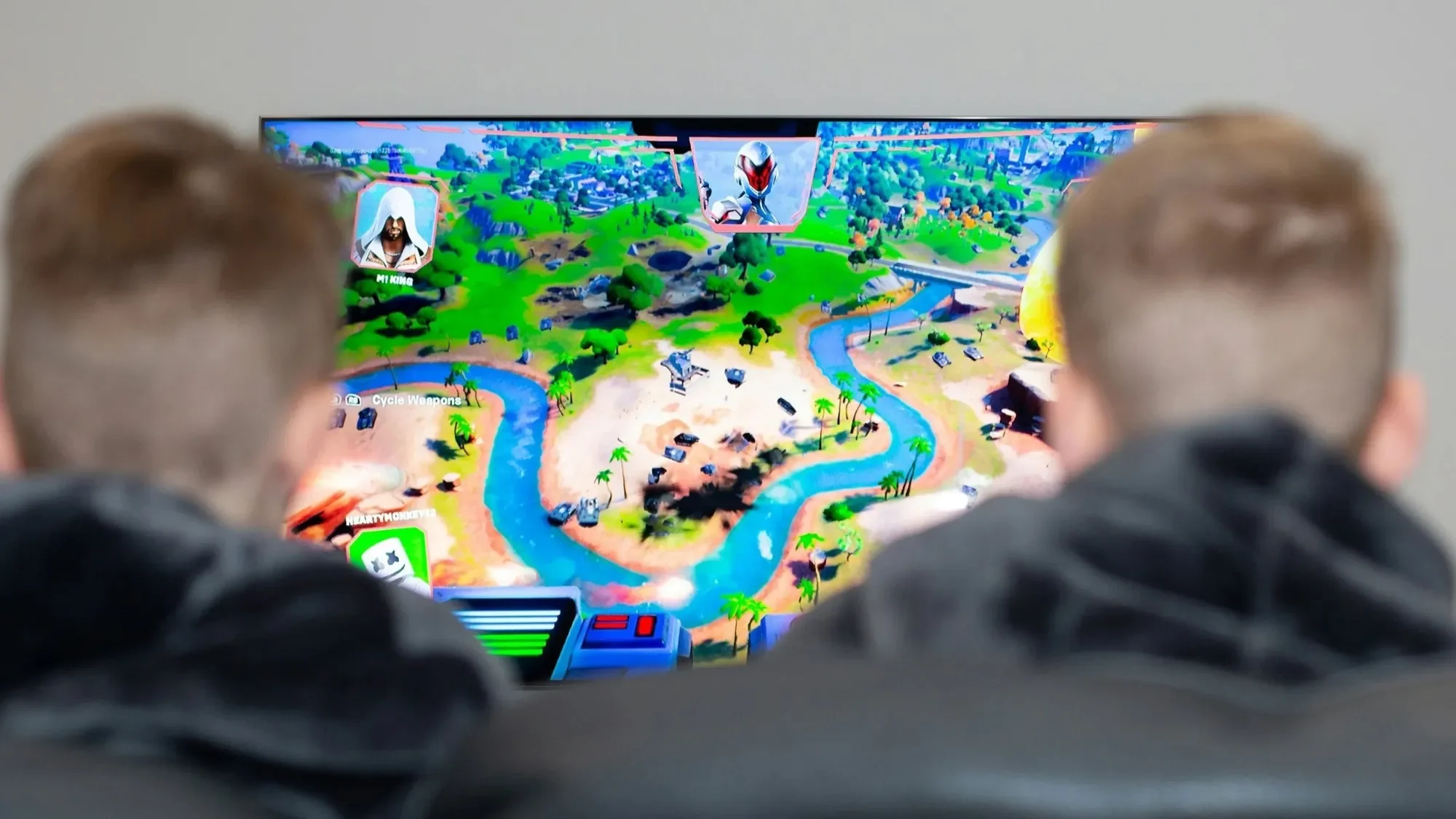Two kids playing a colorful video game on a TV