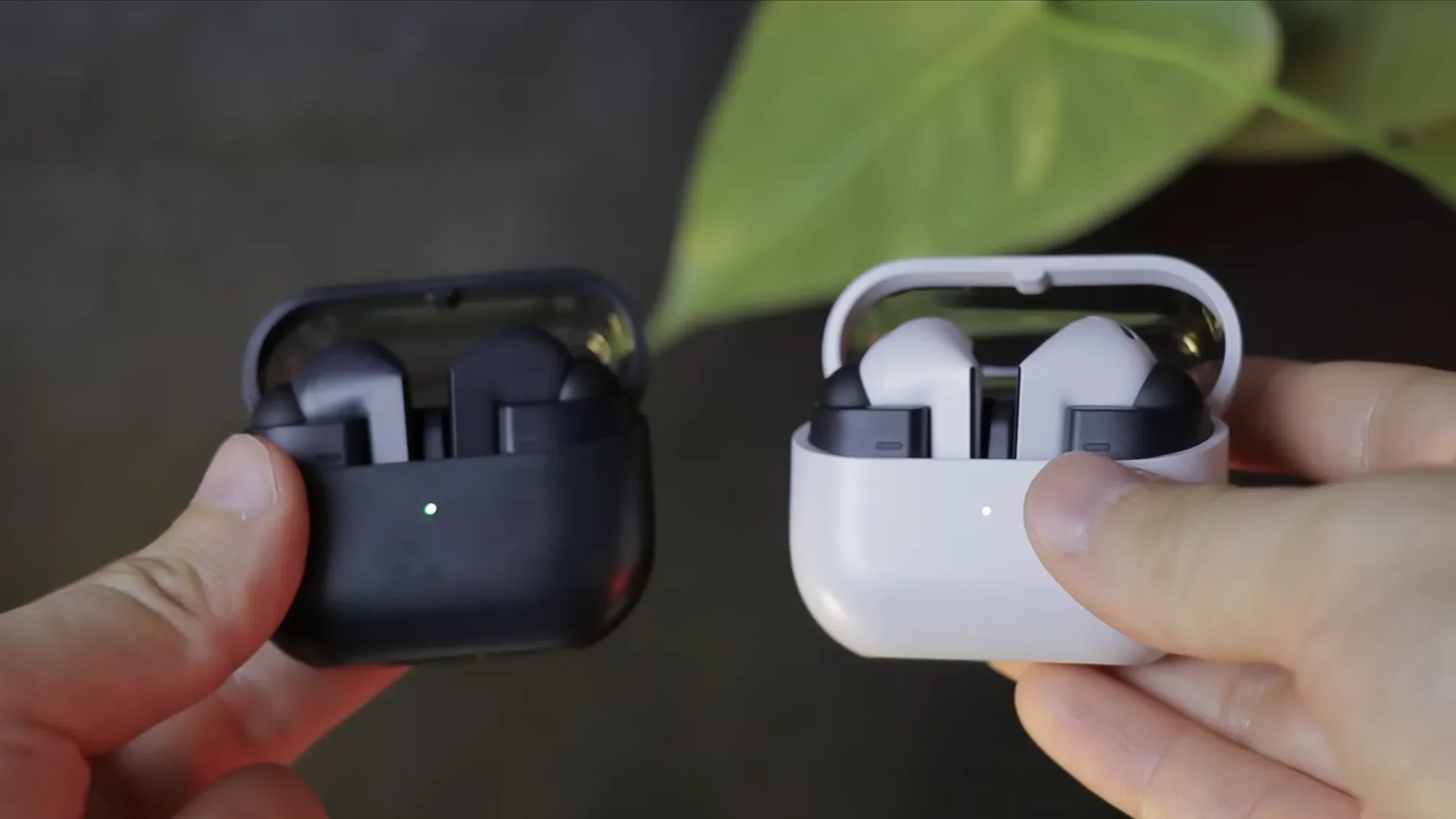 Hands holding Galaxy Buds3 FE cases in black and white