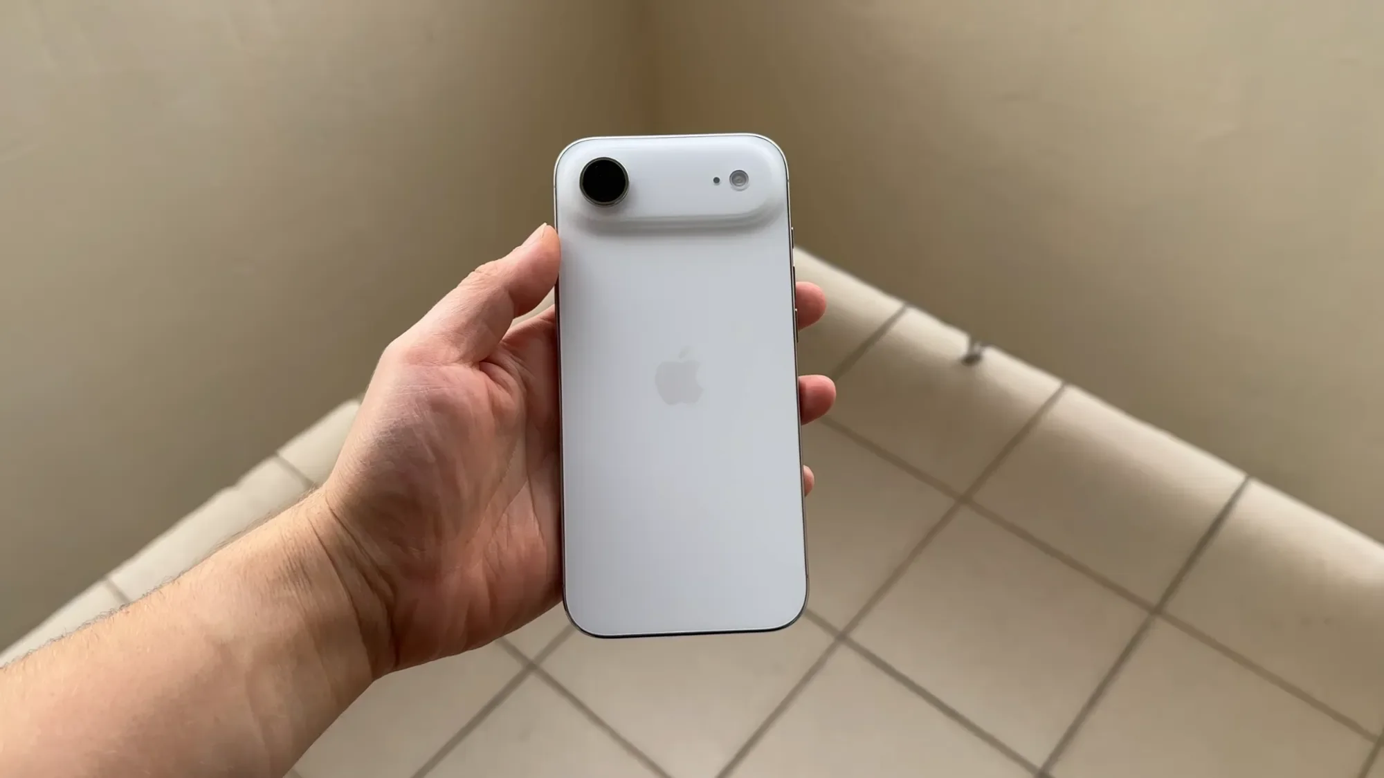 Hand holding a white iPhone Air, seen from the back