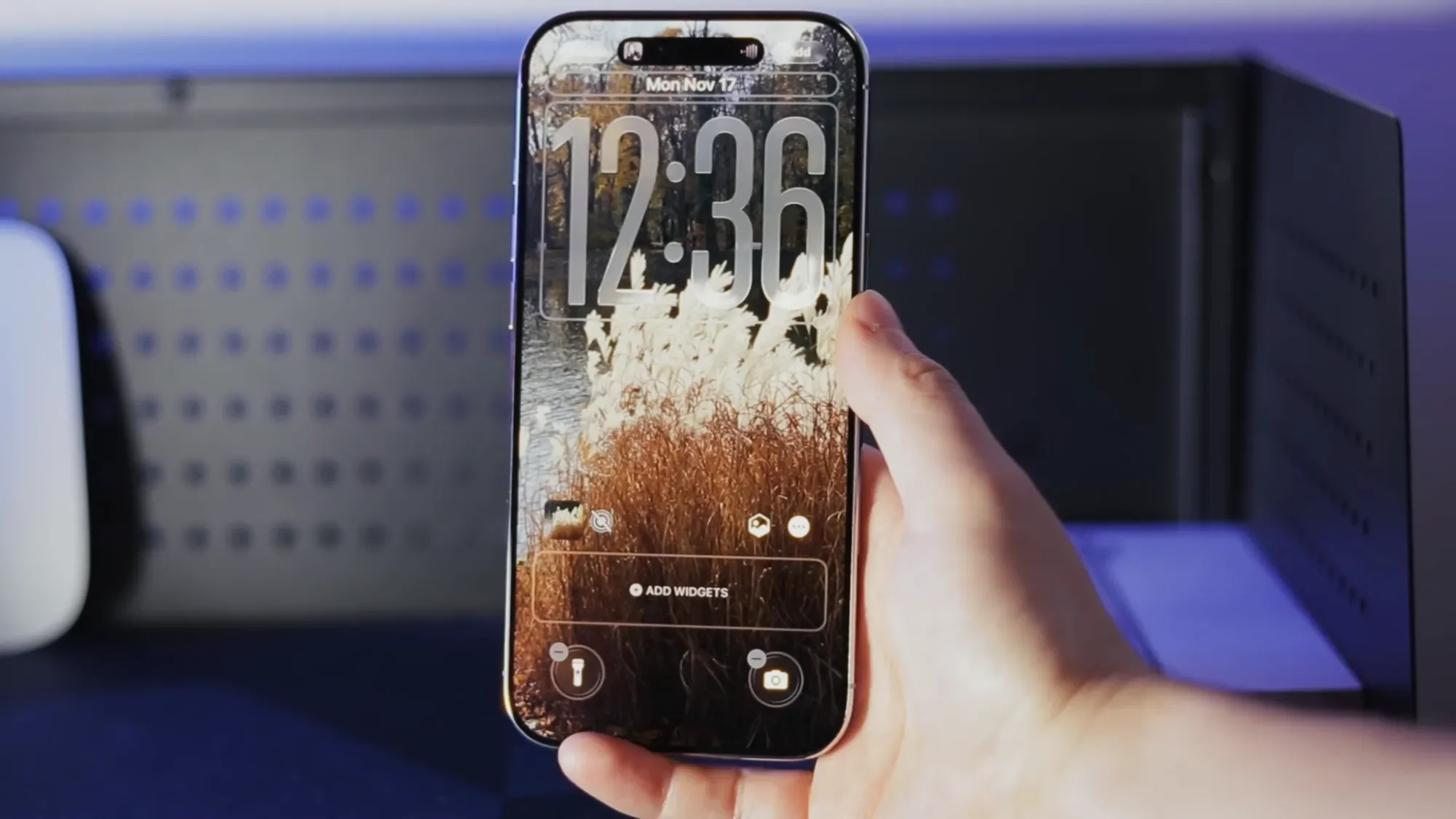 Hand holding an iPhone Air showing the lock screen clock