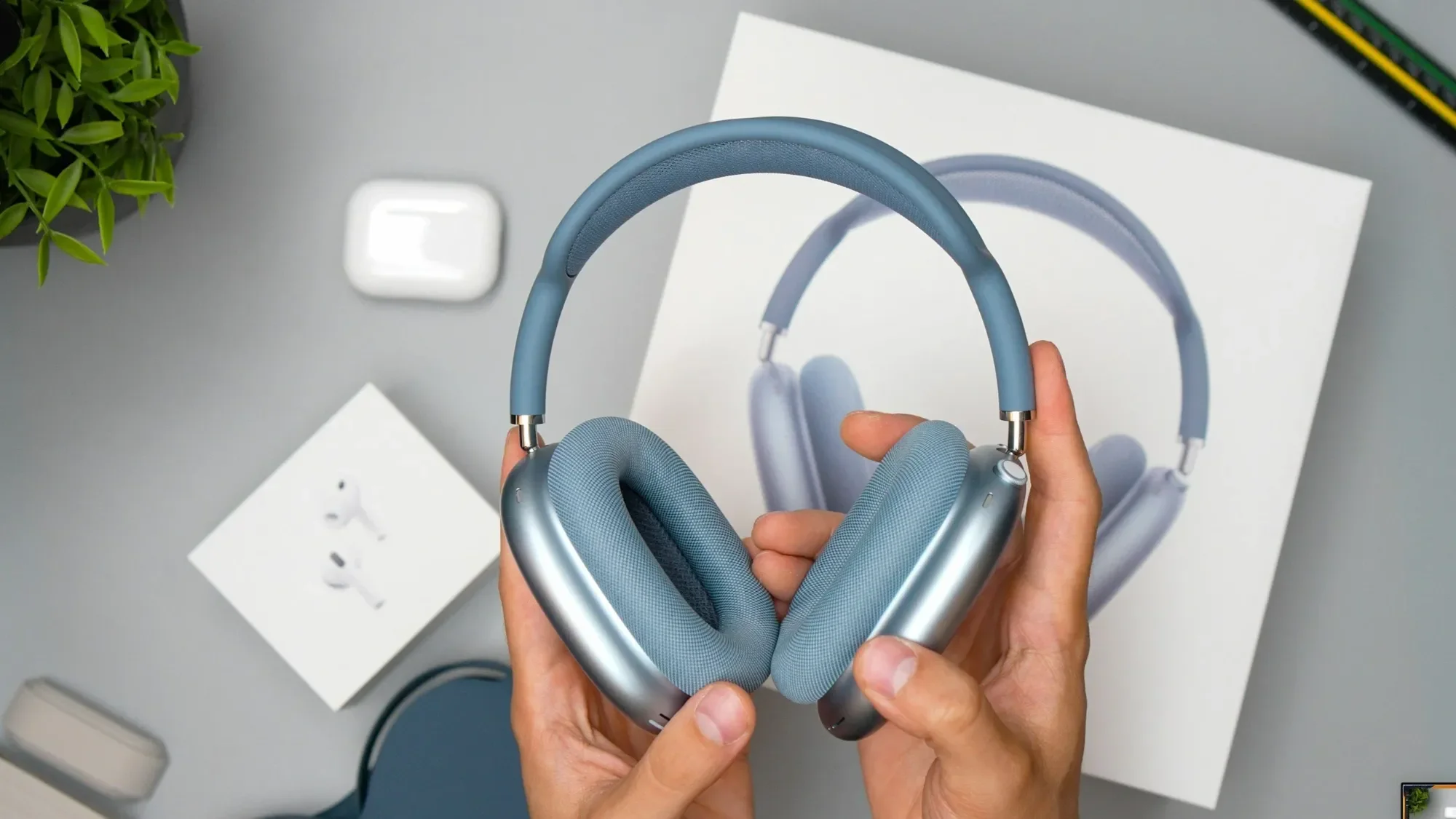 Hands holding blue Apple AirPods Max 2