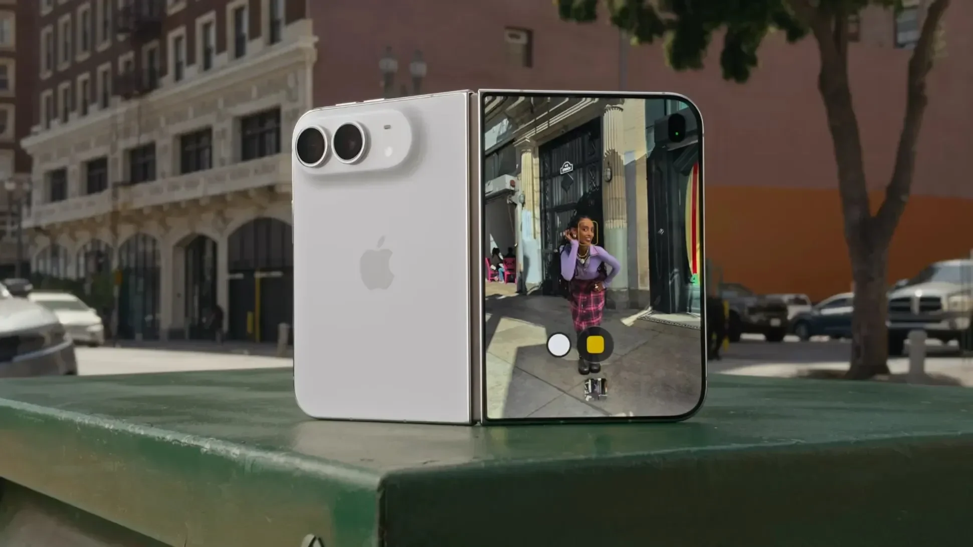White iPhone Duo standing half-folded on a green bench outdoors