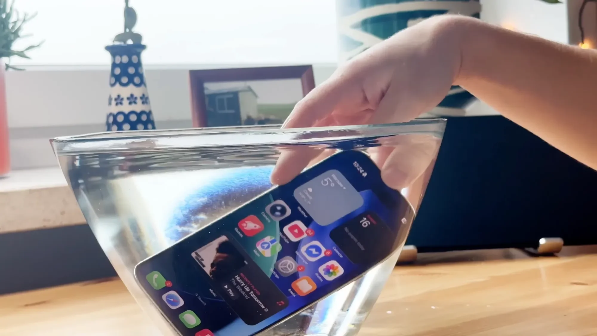 Hand placing an iPhone Air into a bowl of water