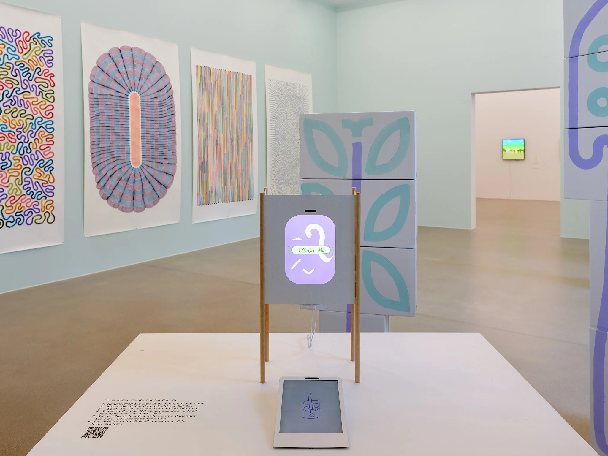 Sai Bot, a cardboard drawing station with a screen reading Touch me, in front of large drawings on paper by Tobias Gutmann at Aargauer Kunsthaus