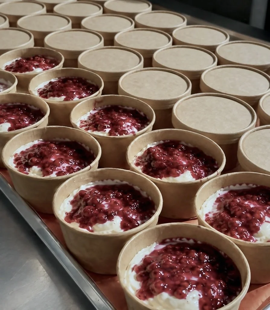 Several bowls filled with yogurt topped with berry compote, arranged in rows on a tray.