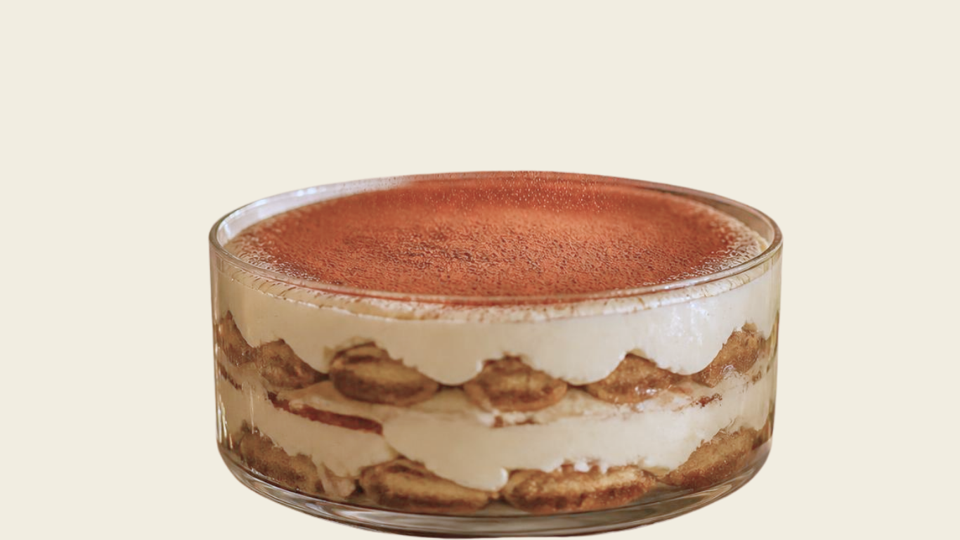 Tiramisu in a glass dish with layers of coffee-soaked ladyfingers and mascarpone cream, topped with cocoa powder.