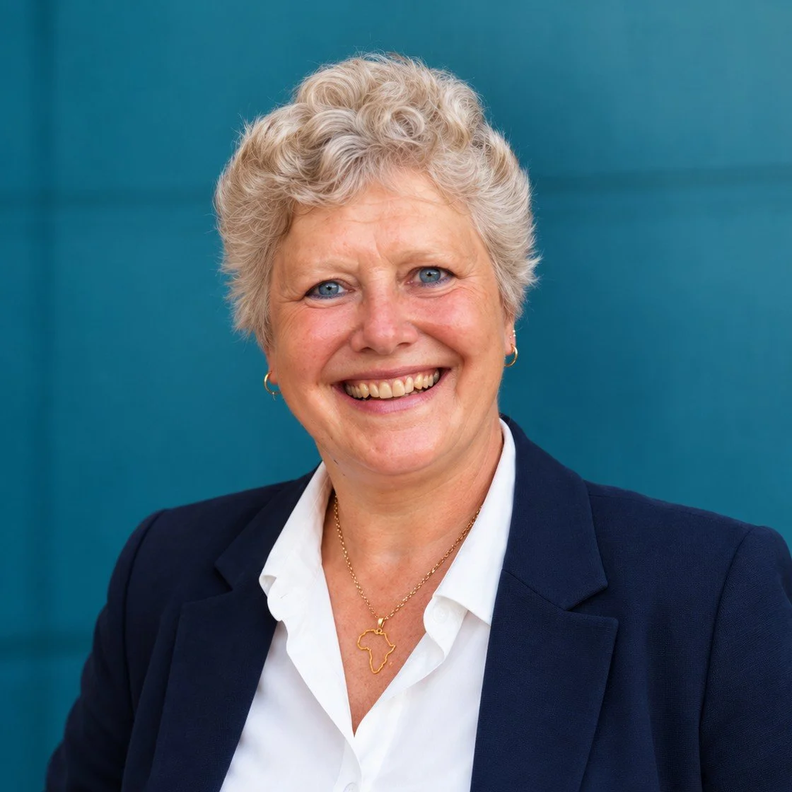 Porträt von Dr. Angela Daalmann im dunkelblauen Blazer vor petrolfarbenem Hintergrund, Speakerin, Business Coachin und Trainerin