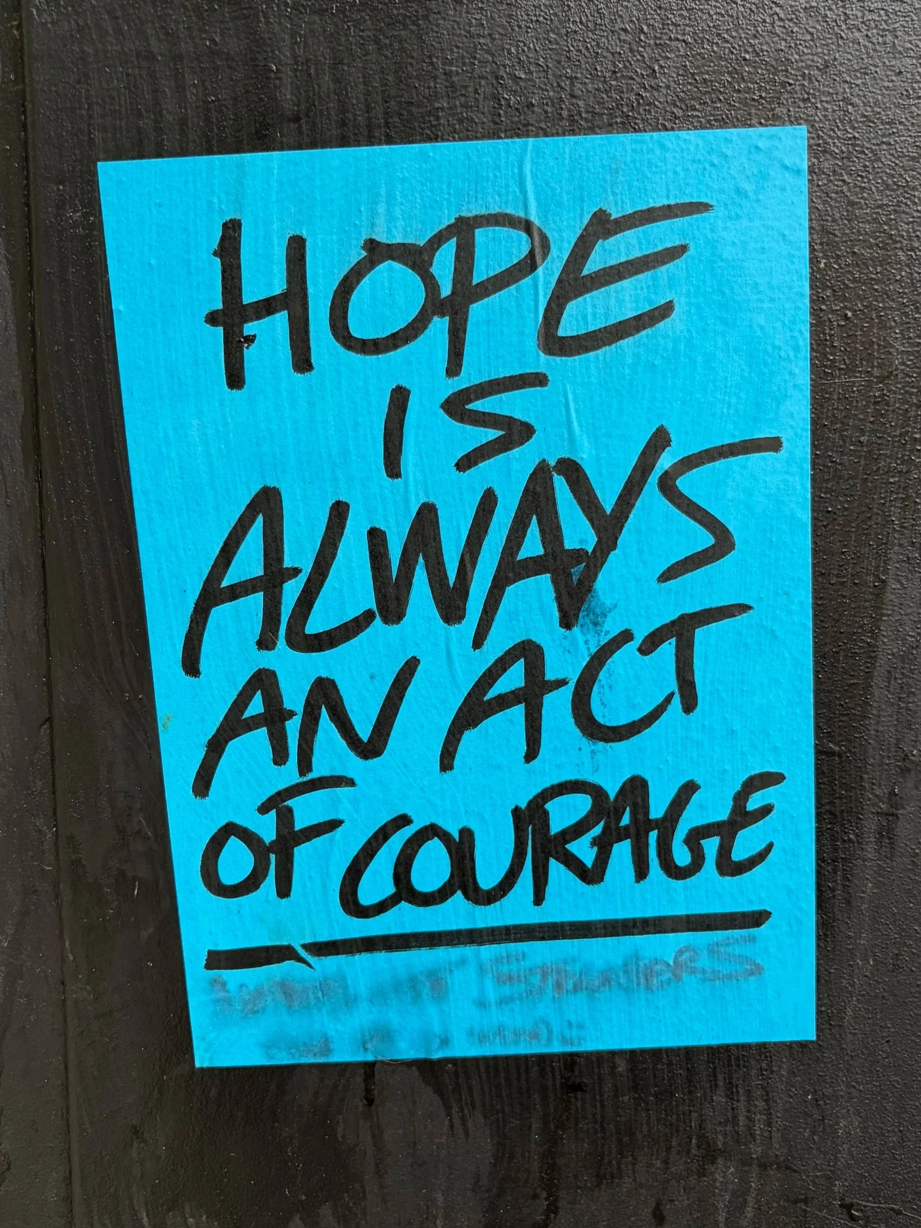 Blue paper with handwritten message in black ink that reads 'Hope is always a fact of your face'.