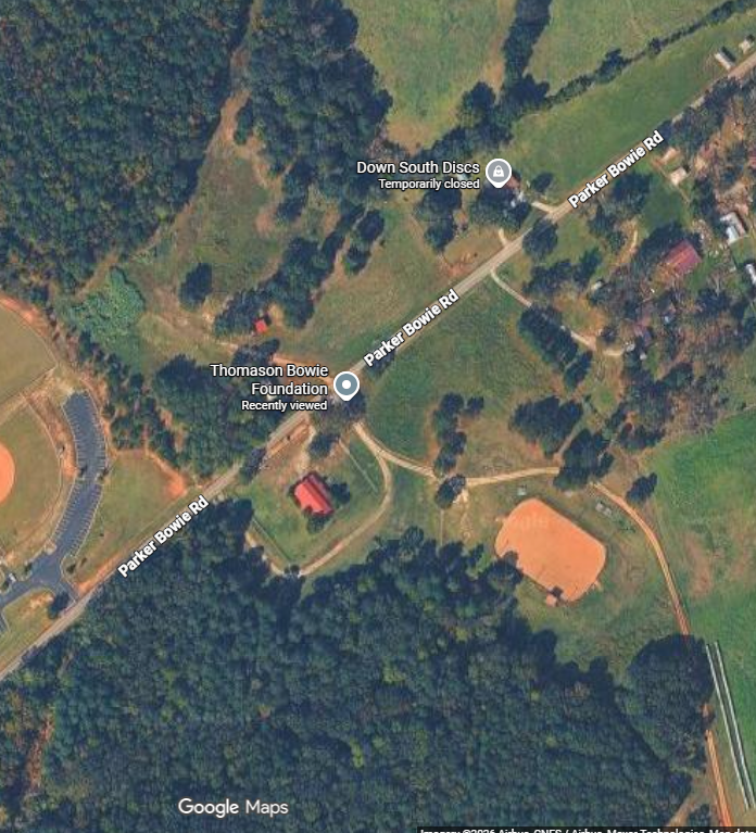 Aerial view of Parker Bowie Road with nearby Thompson Bowie Foundation and Down South Discs, surrounded by trees, fields, a baseball field, and some buildings.