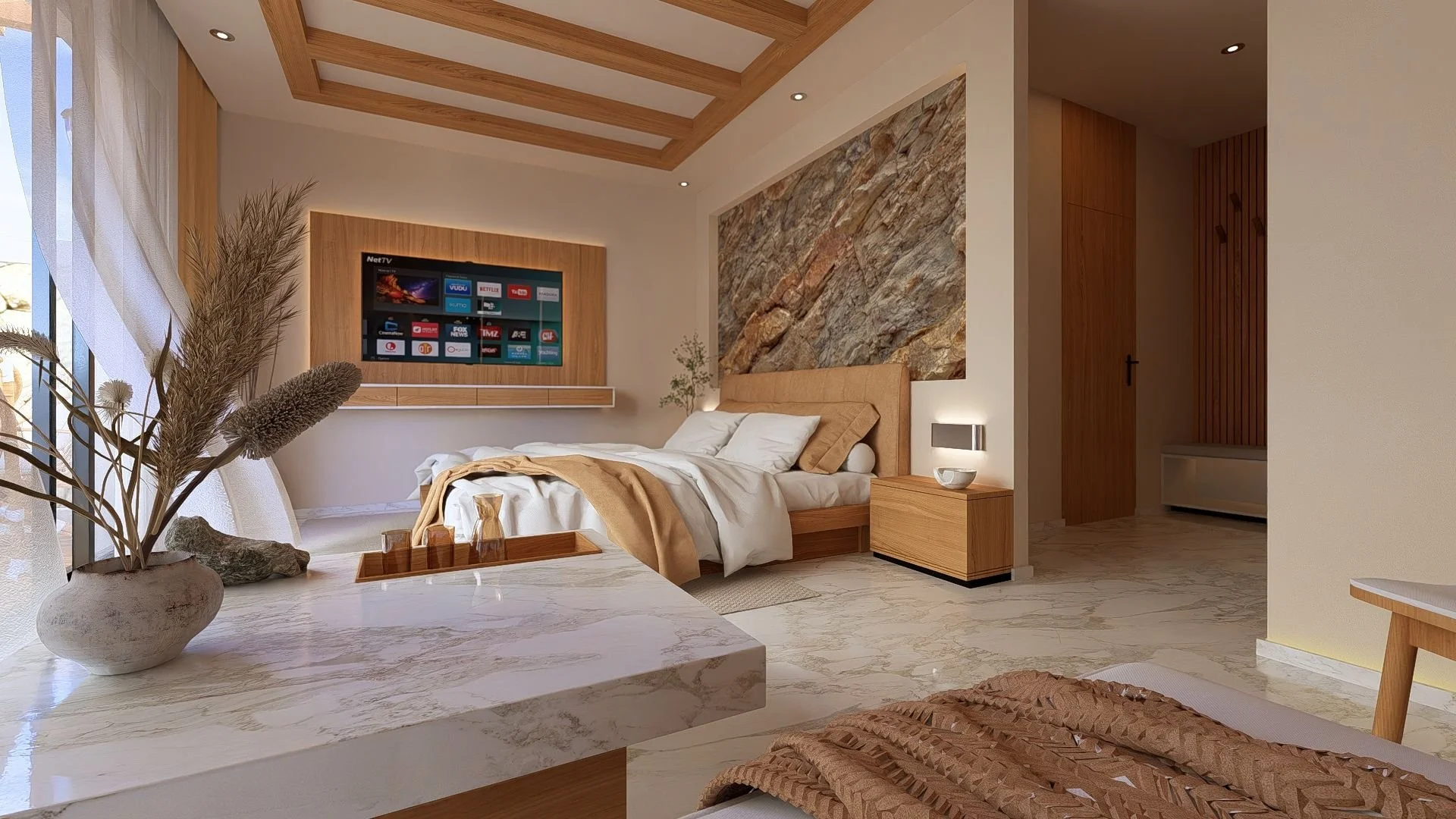 Et rom med seng med beige hodegavl og hvite og beige sengetøy. Veggen bak sengen har en dekorativ steinvegg. Det er en flatskjerm-tv på veggen med trekanter av tre som ramme rundt. Det er et nattbord med en væske ved siden av sengen. På bordet er det