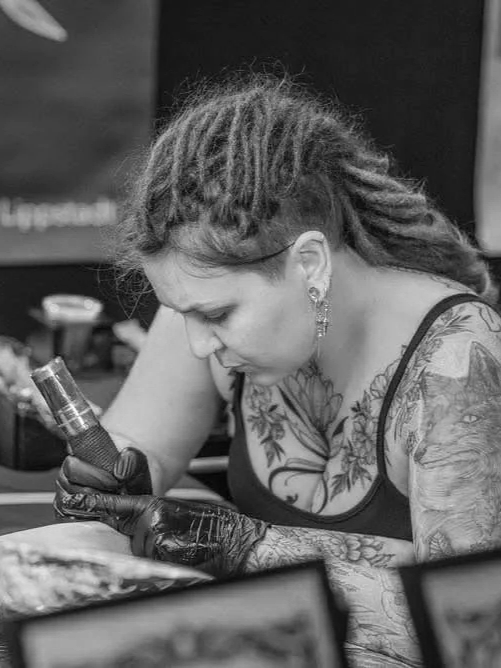 Tattoo-Künstlerin tätowiert einen Kunden bei einer Tattoo-Session auf einer Tattoo Convention.