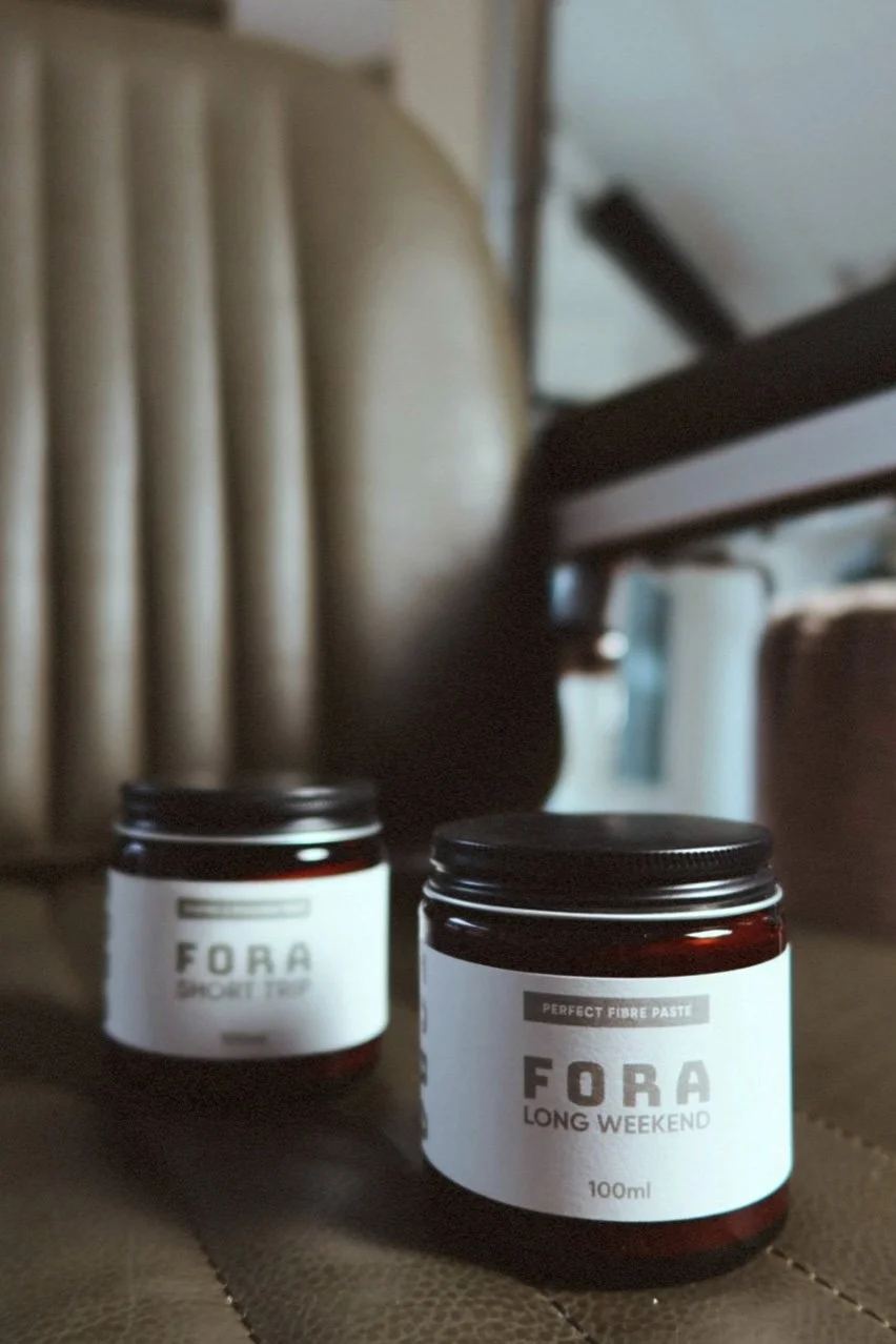 Two jars of Fora supplement placed on a surface with furniture in the background.