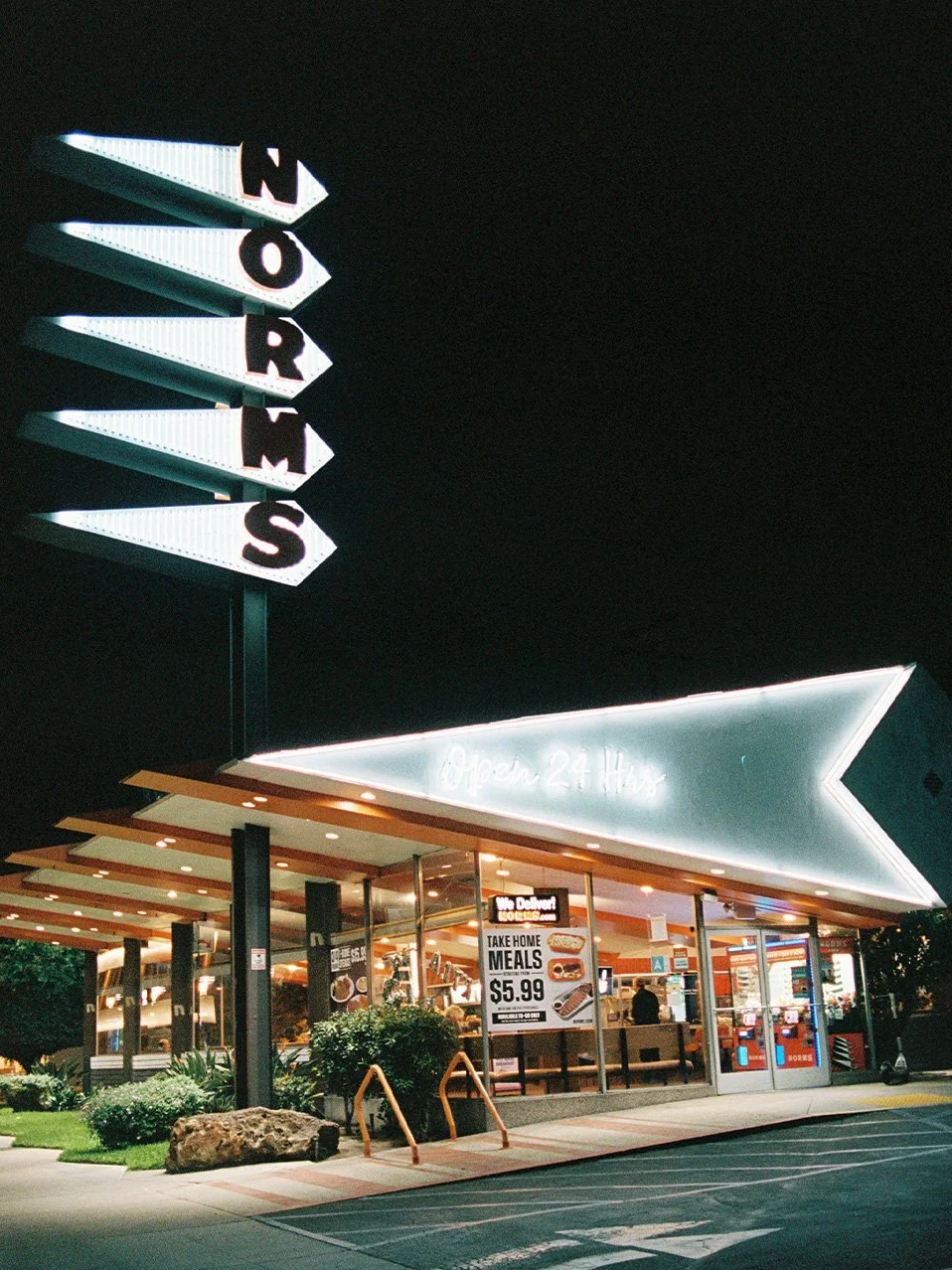 Night view of a Sonic Drive-In fast-food restaurant with illuminated signs, outdoor seating, and menu advertisements.